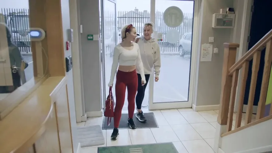 Two guests walk in through the front door towards reception.
