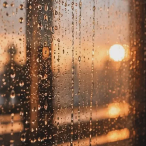 Rain running down a window at sunset